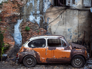 Old abandoned rusty car on old brick wall background