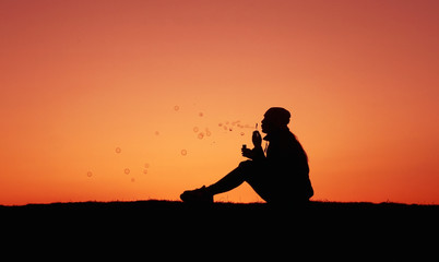 Silhouettes girl at sunset, girl blows bubbles, incredible sunset