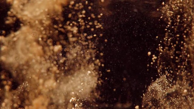 Golden glitter gets into the water with a black background and settles down. upside down.