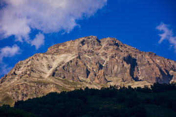 Peaks of mountains in the neighborhood of Dombai. Caucasus Mountains summer, clear day from the forest.