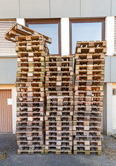 Stapel von gebrauchten Paletten aus Holz in einem Hinterhof