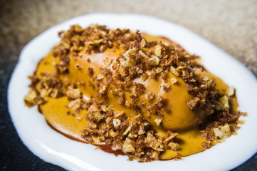 baked sweet potato with mango sauce, black background, top view