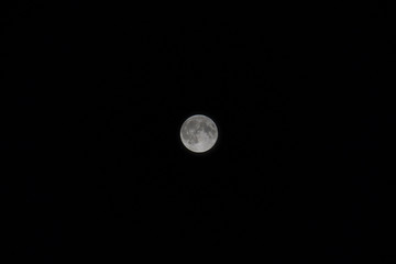 Small full moon with black sky at night time.