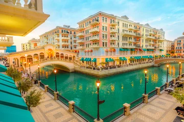 Fotobehang Aerial view of two Venetian bridges on canals of picturesque and luxurious district of Doha illuminated at blue hour. Scenic Venice at Qanat Quartier in the Pearl-Qatar, Persian Gulf, Middle East. © bennymarty