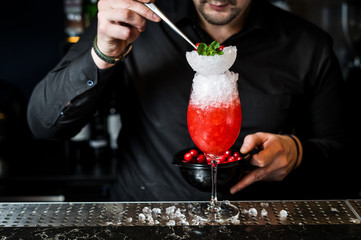 Bartender prepares Margarita cocktail, dark background, close-up