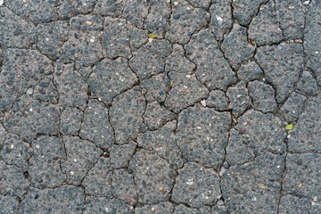 Broken stone grey blue background with embedded stones - cracked tarmac texture with orange and teal tinge tint