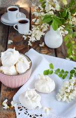 Meringues cookies and cup of coffee. Homemade Meringue kisses drops with acacia flowers. Vintage photo. Copy space.