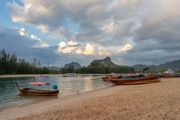 Fototapeta premium Boat station on Nopparat Thara pier and local authentic boats under dramatic clouds on sky in Ao Nang in Krabi province in Thailand