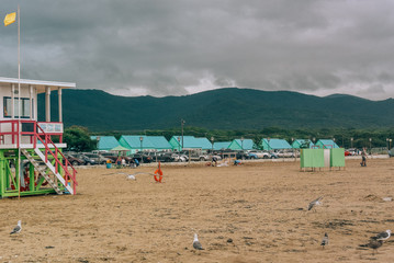 Fototapeta na wymiar beach, wooden huts, lifeguard house, seagulls, mountains, sand