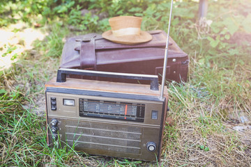 Retro radio and straw hat are lying on the old leather suitcase. Travel lifestyle concept. Vintage...