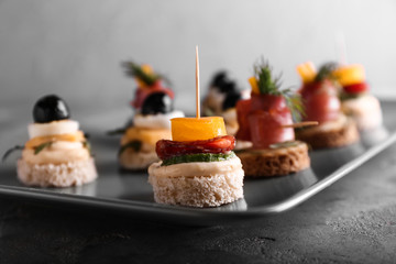 Plate with tasty canapes on grey table, closeup