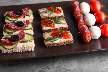 Plate with tasty canapes on grey table