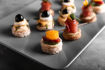 Plate with tasty canapes on grey table, closeup