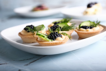 Plate with tasty canapes on light table, closeup