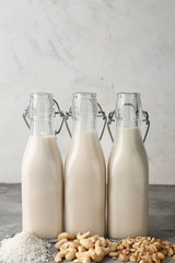 Assortment of tasty vegan milk on grey table
