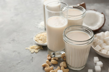 Assortment of tasty vegan milk on grey table