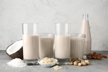 Assortment of tasty vegan milk on grey table