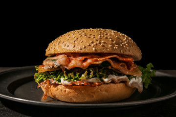 Tasty burger on dark plate, closeup
