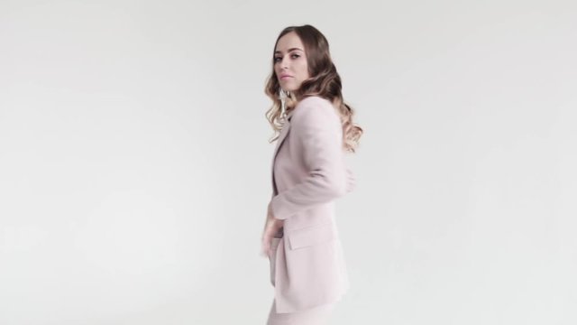Business lady posing in a white jacket and trousers on a white background. Sexy woman unbuttoned her jacket, 50 frames per second