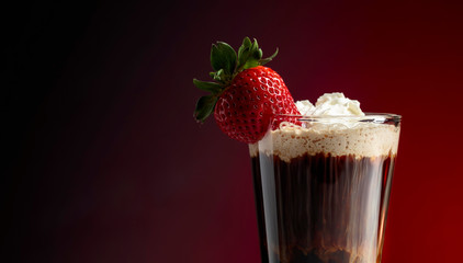 Chocolate drink with whipped cream and strawberry on a dark background.