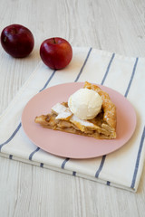 Slice of home-baked apple pie with ice cream on pink plate, side view. Closeup.