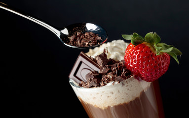 Chocolate drink with whipped cream, strawberry and pieces of black chocolate.
