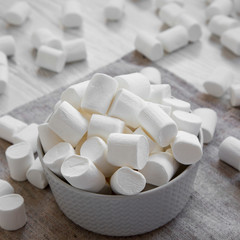 Fluffy white marshmallows in a gray bowl, side view. Close-up.