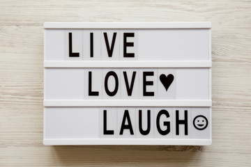 Modern board with words "Live Love Laugh' over white wooden background, top view. Flat lay, overhead, from above.