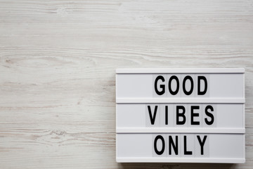 'Good vibes only' words on lightbox over white wooden background, top view. From above, overhead,...