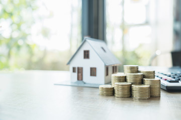 Saving money for house and real estate. Woman hand protecting on stack coins and house model on...