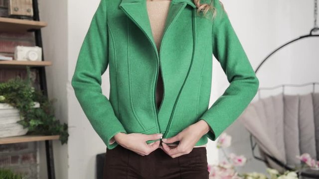 the girl fastens a zipper coat of green color. close-up.