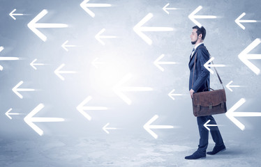 Businessman walking with arrows on the background and briefcase on his hand
