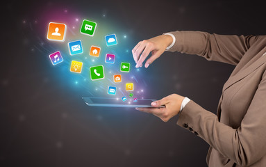 Hand holding tablet and application icons falling inwards
