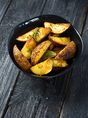 Country potato crispy on a dark wooden table . Fast food French fries