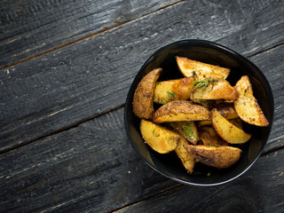 Country potato crispy on a dark wooden table . Fast food French fries
