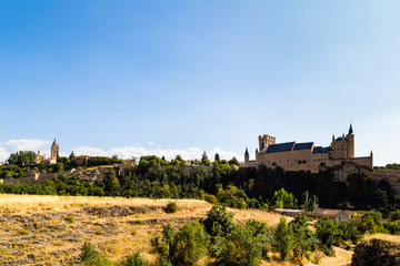 Fototapeta na wymiar View of Segovia Old Town in Summer from the field next to Iglesia de la Vera Cruz, an ancient Templar church. Castilla Y Leon, Spain. Cathedral and Alcazar are visible in the picture
