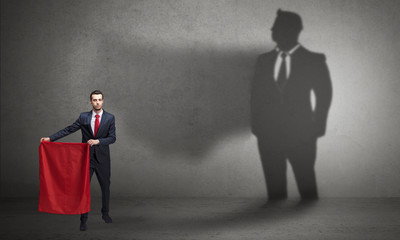 Obraz premium Businessman standing with red cloth on his hand and his shadow on the background 