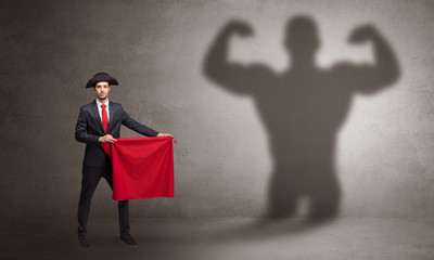 Businessman standing with red cloth on his hand and strong hero shadow on the background
