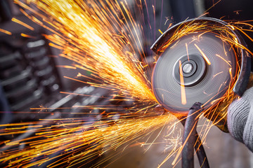 A close-up of a car mechanic using a metal grinder to cut a car bearing  in an auto repair shop,...