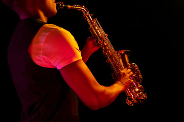 African American handsome jazz musician playing the saxophone in the studio on a neon background....