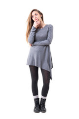 Young worried woman in gray tunic thinking and looking up with hands on chin. Full body isolated on white background. 