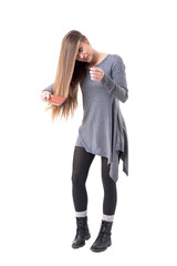 Young stylish woman brushing and taking care of her long healthy hair. Full body isolated on white background. 