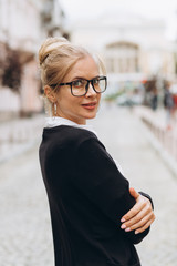 Fototapeta premium Beautiful trendy blond business woman in glasses with folder of documents in her hands outdoors.