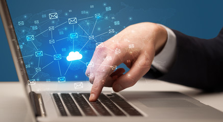 Businessman hand sending a bunch of messages on laptop with cloud computing concept
