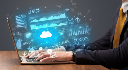 Businessman hand typing on laptop with reports and graphs concept around
