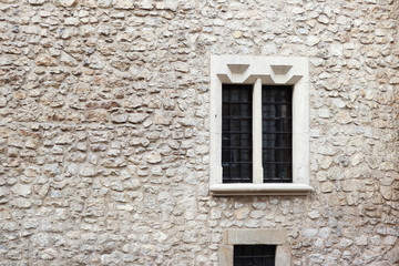 Fototapeta na wymiar Old stone wall and cement with old window. Stone background. Krakow stone wall. Griddles on the windows. Krakow building