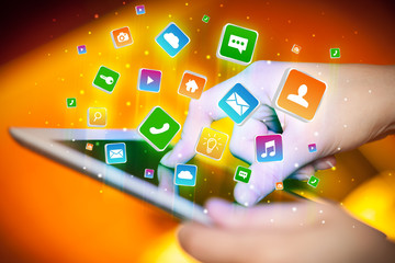 Businessman hand using tablet with flying application icons around
