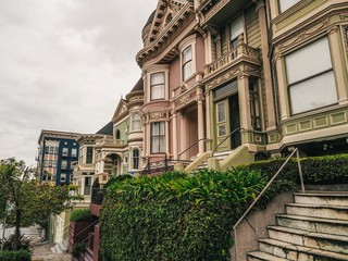 Victorian multicolored houses in San Francisco, street on a cloudy day, beautiful stairs