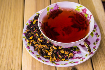 cup of herbal tea with spices on a light wooden background