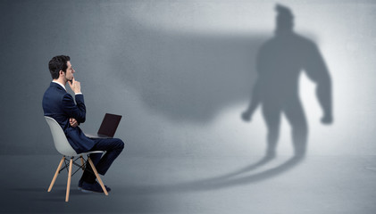 Humble businessman staying and offering stuffs to a superhero shadow
